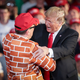 President Donald Trump calls up Blake Marnell, wearing a jacket with bricks representing a border wall, to the stage during a ‘Make America Great Again’ campaign rally.